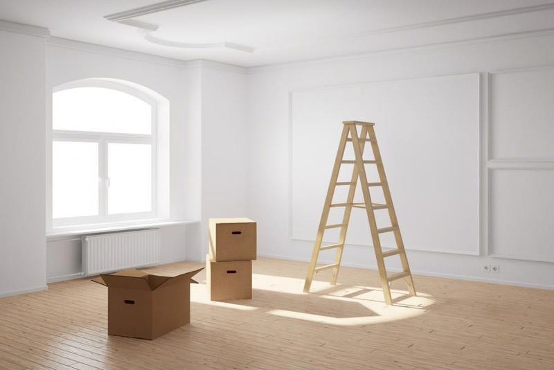 A mostly empty room with a few boxes inside, bathed in sunlight from a large window.