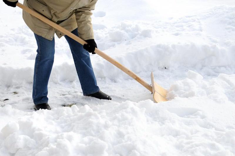 A person shoveling their home's walkway.