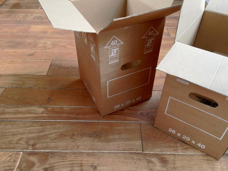 A pair of moving boxes sitting on a hardwood floor.
