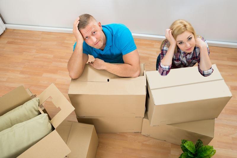 Couple with moving boxes looking frustrated. 
