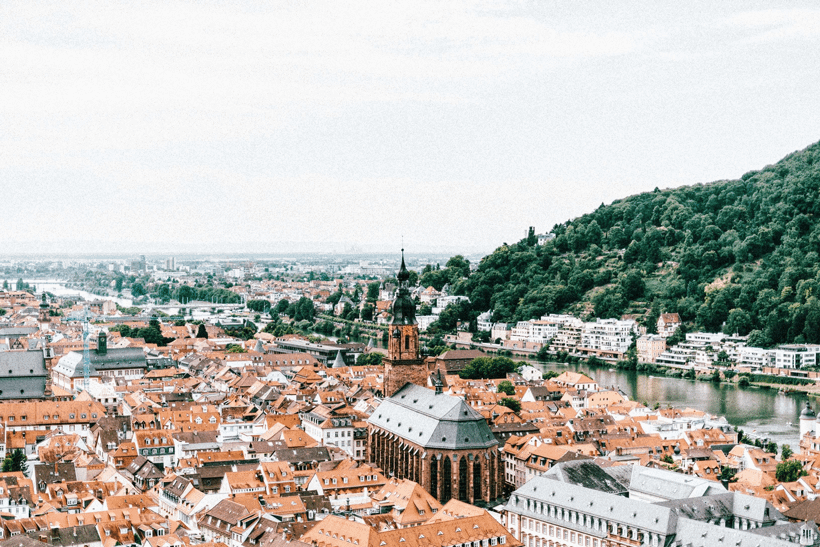 aerial view of Heidelberg, Germany with old, brown rooftops and a green mountainside