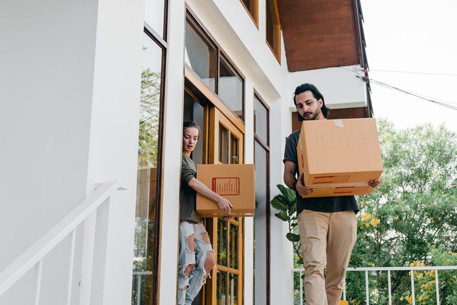 Man and woman carrying boxes out of a house